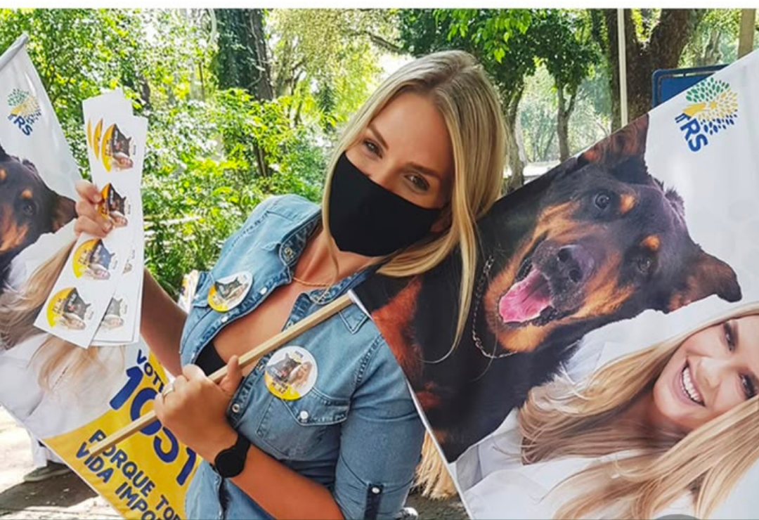 Bruna Molz segurando bandeiras de campanha com estampa de cães, campanha de 2020
