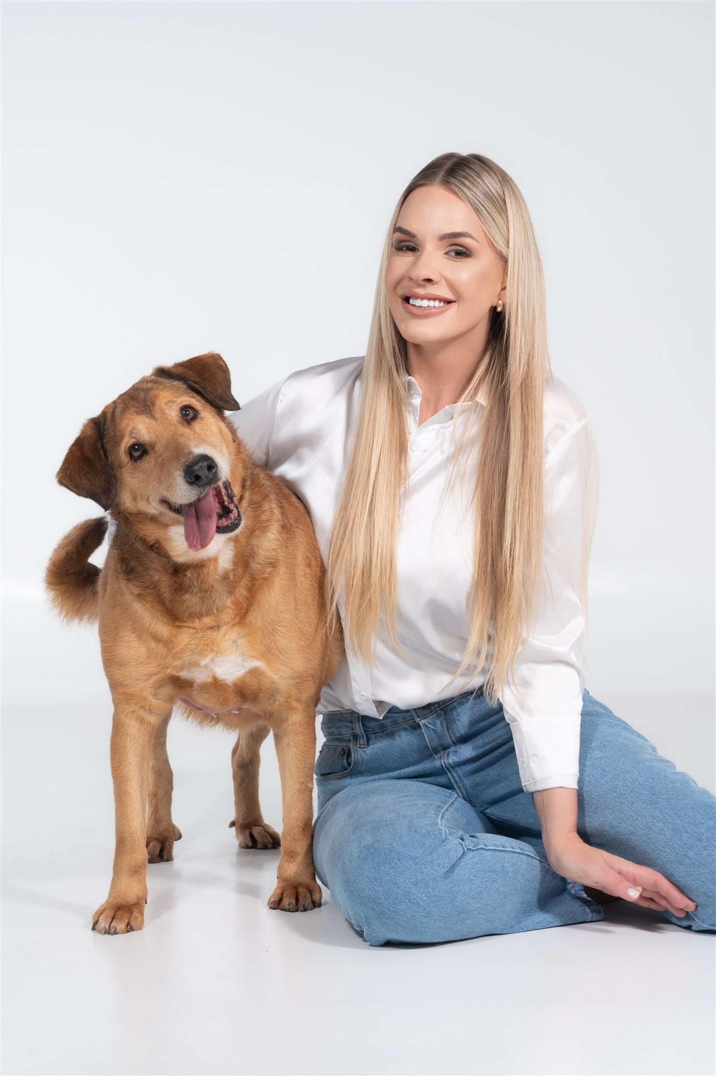 Bruna Molz sorrindo ao lado de seu cão resgatado, foto de estúdio